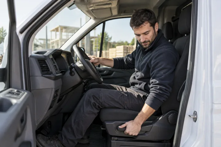 Conductor ajustando el asiento de una furgoneta de trabajo estacionada