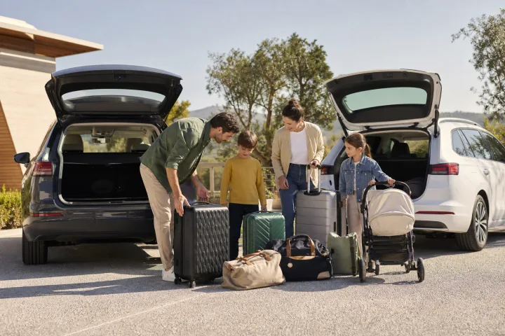 Familia comparando el espacio de carga de dos coches con maletas y un carrito infantil junto a ellos.